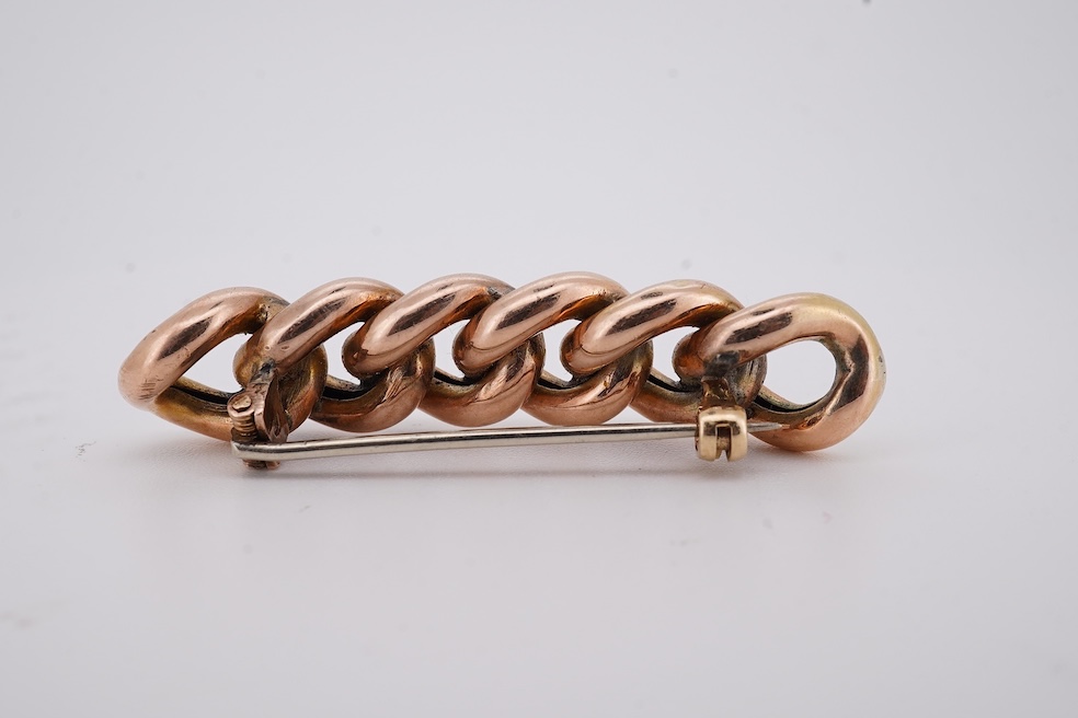 An early 20th century yellow metal and graduated five stone coral bead brooch, with seed pearl spacers, 45mm, together with a yellow metal curb link brooch and a yellow metal (stamped 9c) safety pin. Condition - fair
